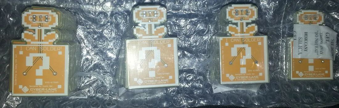Batch of flower-shaped printed circuit board badges laid out together for assembly.