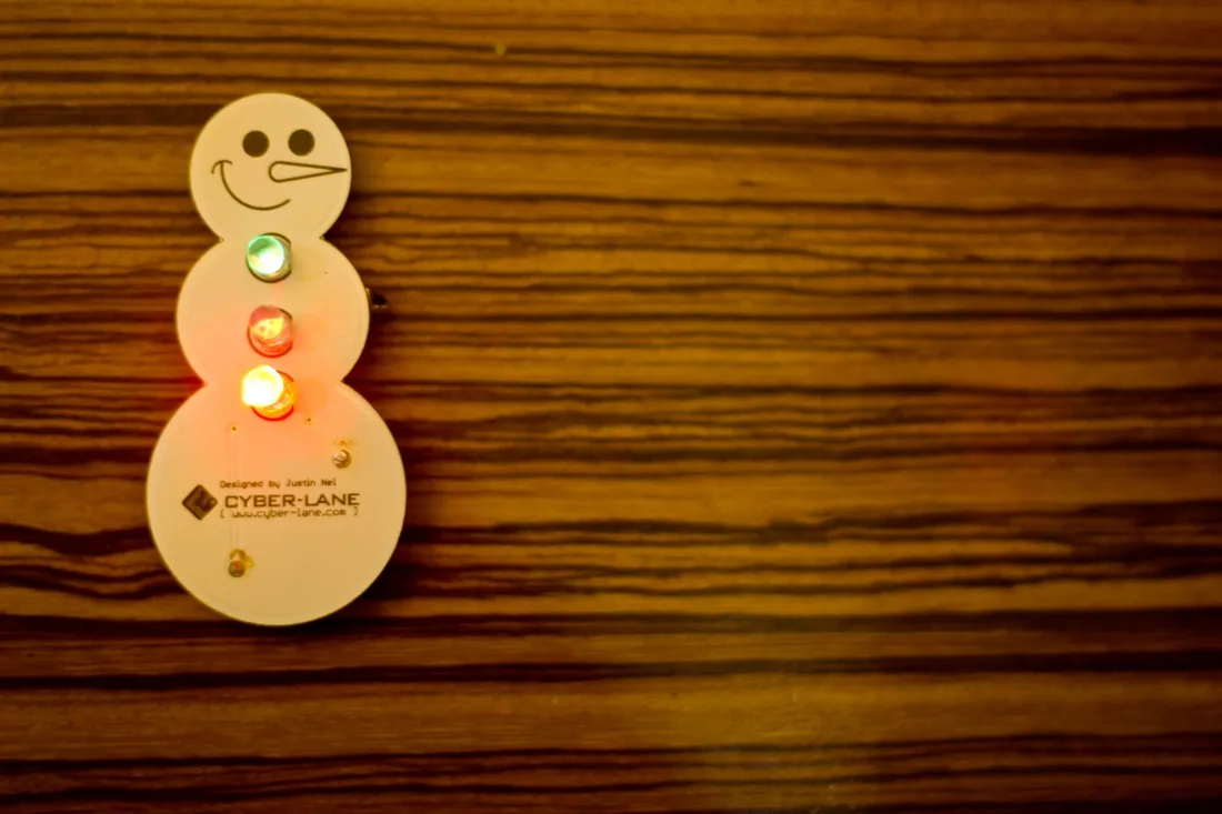 A light-up snowman soldering badge kit for events and workshops.